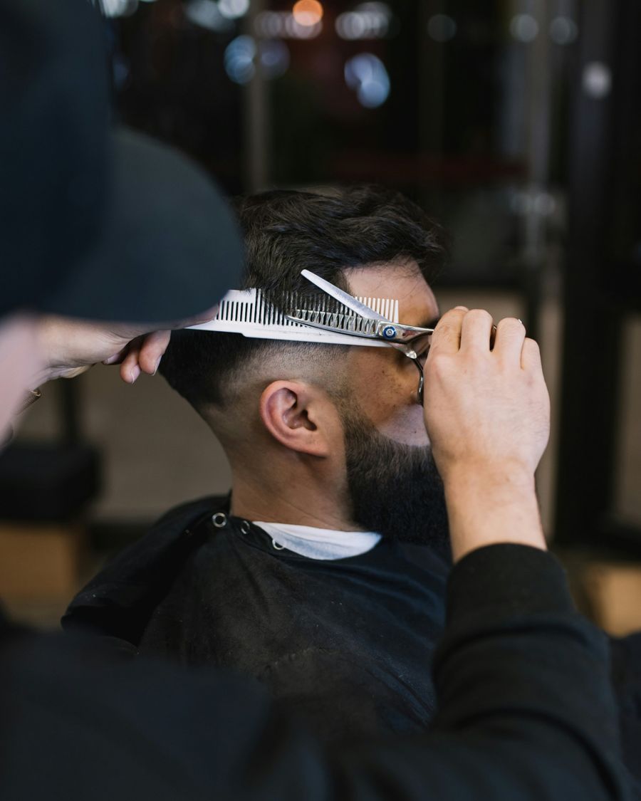 Barbero perfilando el corte a un cliente